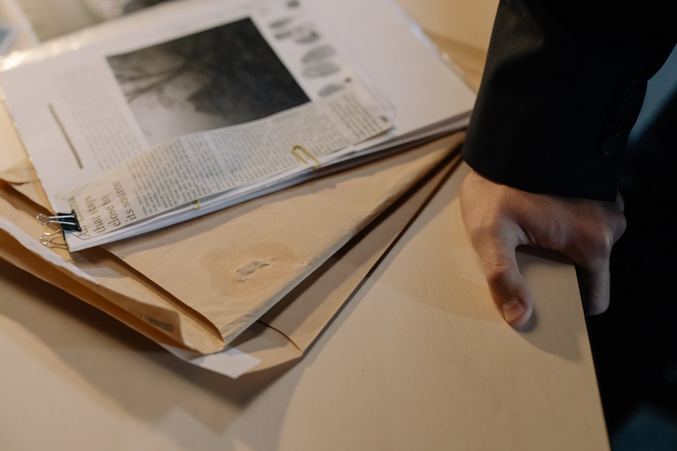 A Person in Black Blazer Holding on to a Desk with Newspaper Clipping